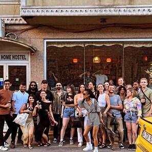 A group of people standing in front of a building with a sign that reads "HOME HOSTEL". - Second Home Hostel (Istanbul)