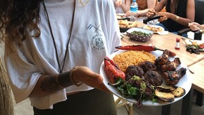 Un espace repas avec des tables, des chaises et un grand barbecue en arrière-plan.