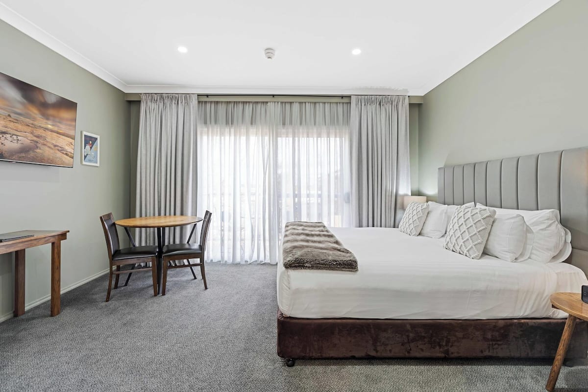 A bedroom with a large bed, a desk, and a chair.