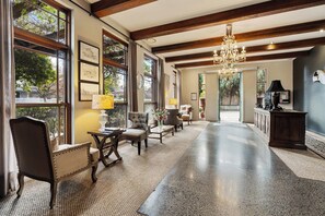 A spacious lobby with a polished concrete floor, large windows with wooden frames, a chandelier, and a seating area with a table and chairs. - de Russie Boutique Hotel Orange (Orange)