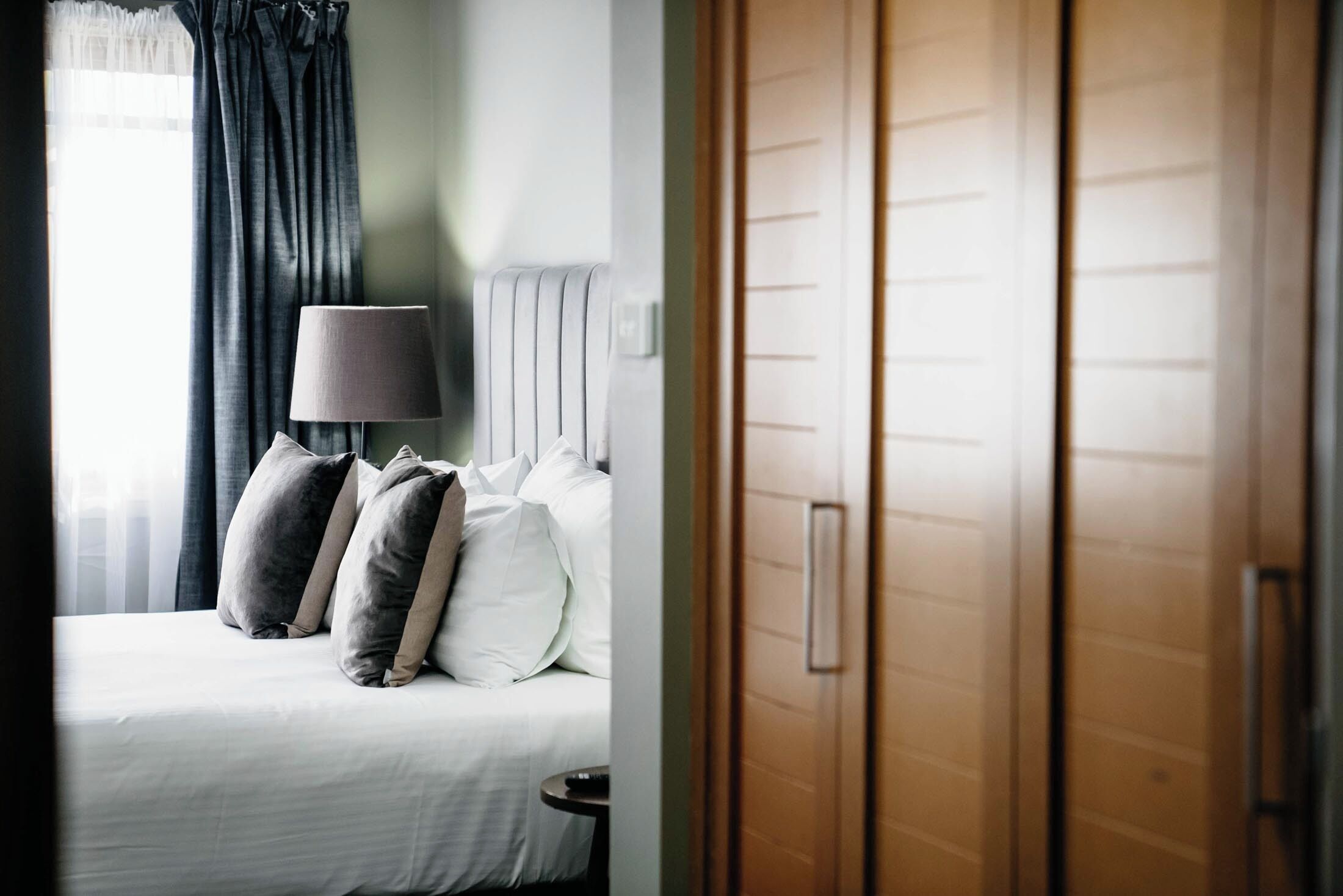 Una habitación de hotel con una cama, una lámpara y un armario de madera.