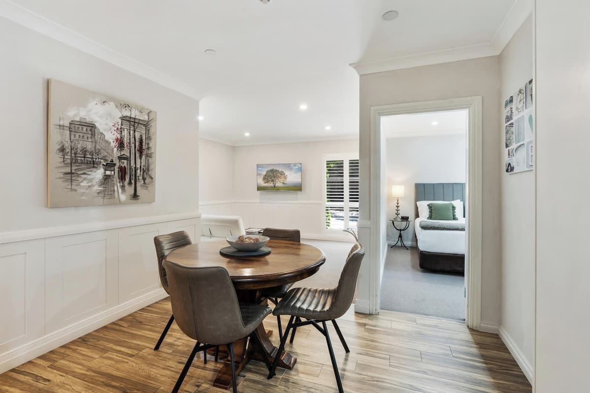 A dining area with a round table, chairs, and a painting on the wall.