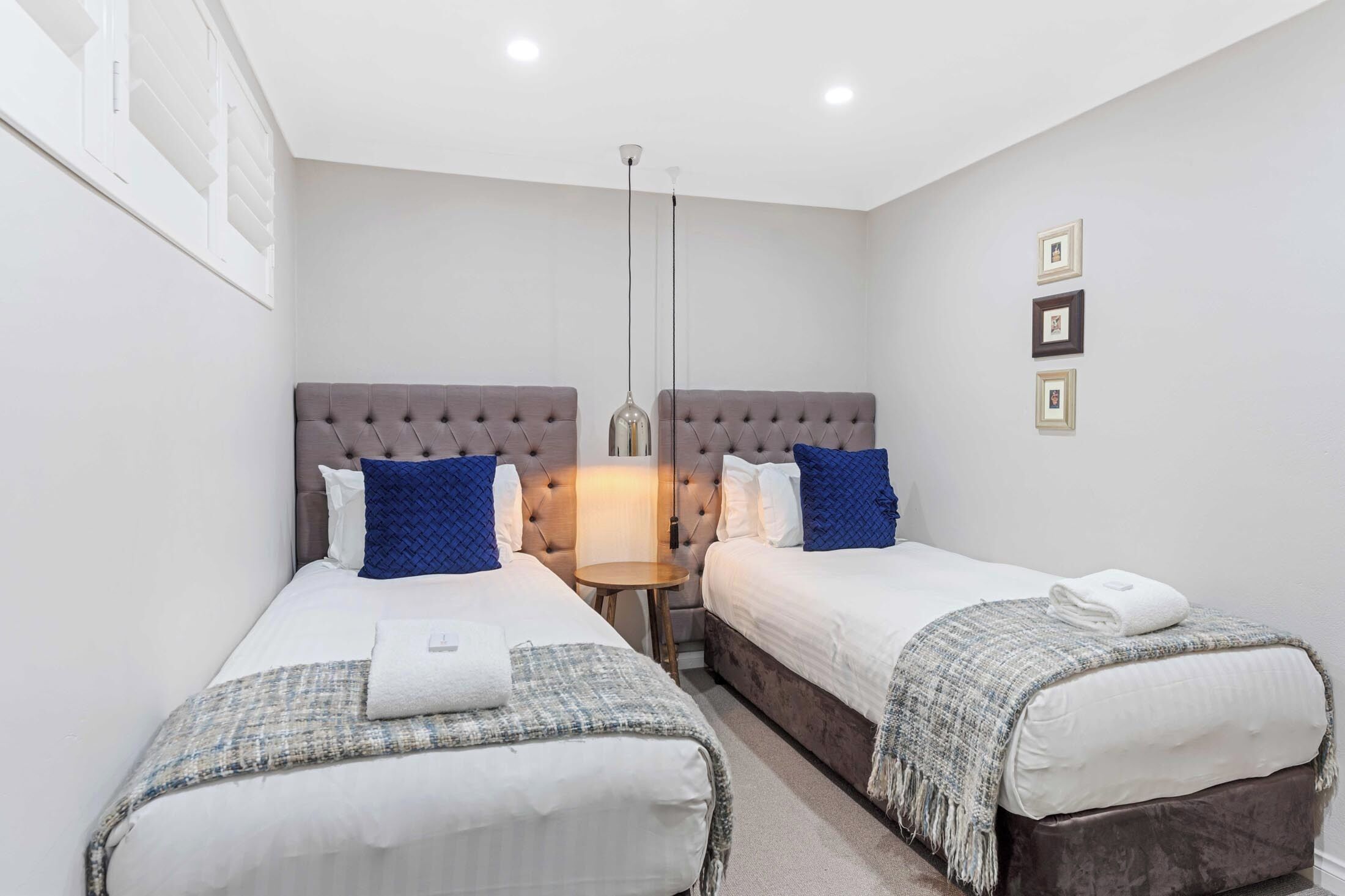 A hotel room with two beds, a small round table, and a lamp.