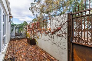 A courtyard with a brick floor, a white wall with vines, and a metal gate. - de Russie Boutique Hotel Orange (Orange)