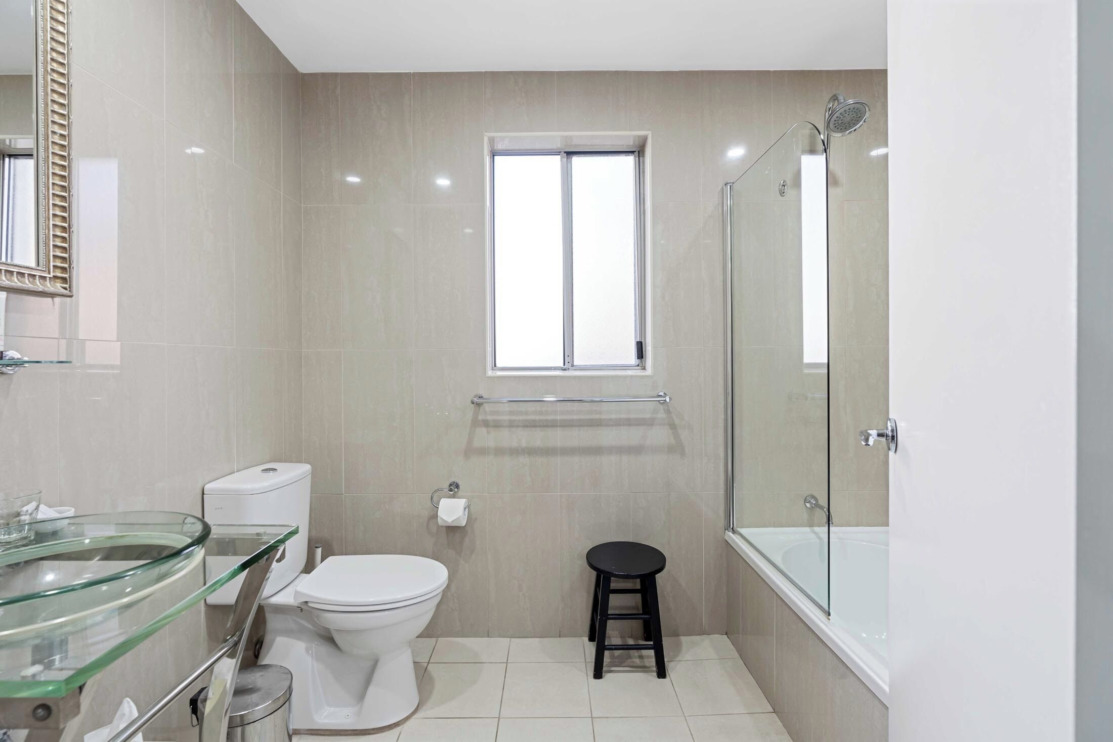 Une salle de bain moderne avec une douche à parois de verre, des toilettes blanches et un lavabo en verre.