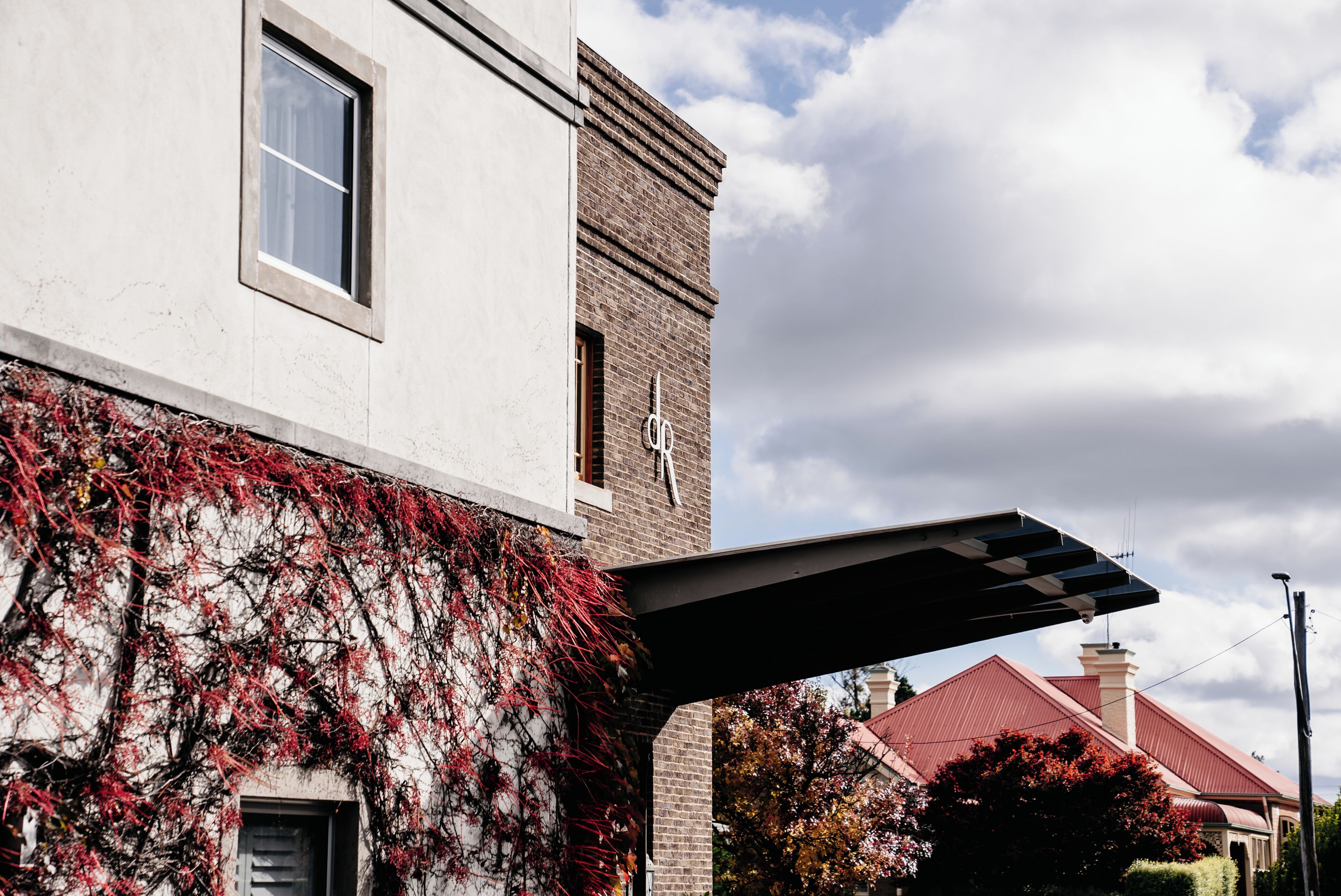 A building with a white facade and red brick section, a window, and a metal awning.