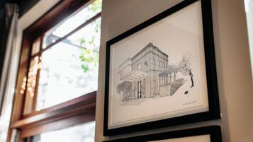 A framed architectural drawing of a building with a balcony and a door, mounted on a wall.