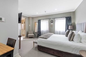 A modern hotel room with a large bed, a desk, a chair, and a TV. - de Russie Boutique Hotel Orange (Orange)