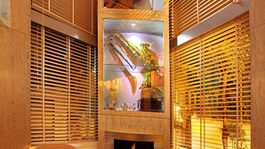Una sala de estar moderna con chimenea, dos sillones anaranjados y una vitrina de cristal con objetos decorativos.