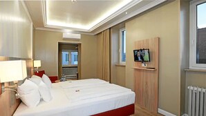 A hotel room with a large bed, a television mounted on the wall, and a window with a view. - Hotel & Restaurant Danner (Rheinfelden (Baden))