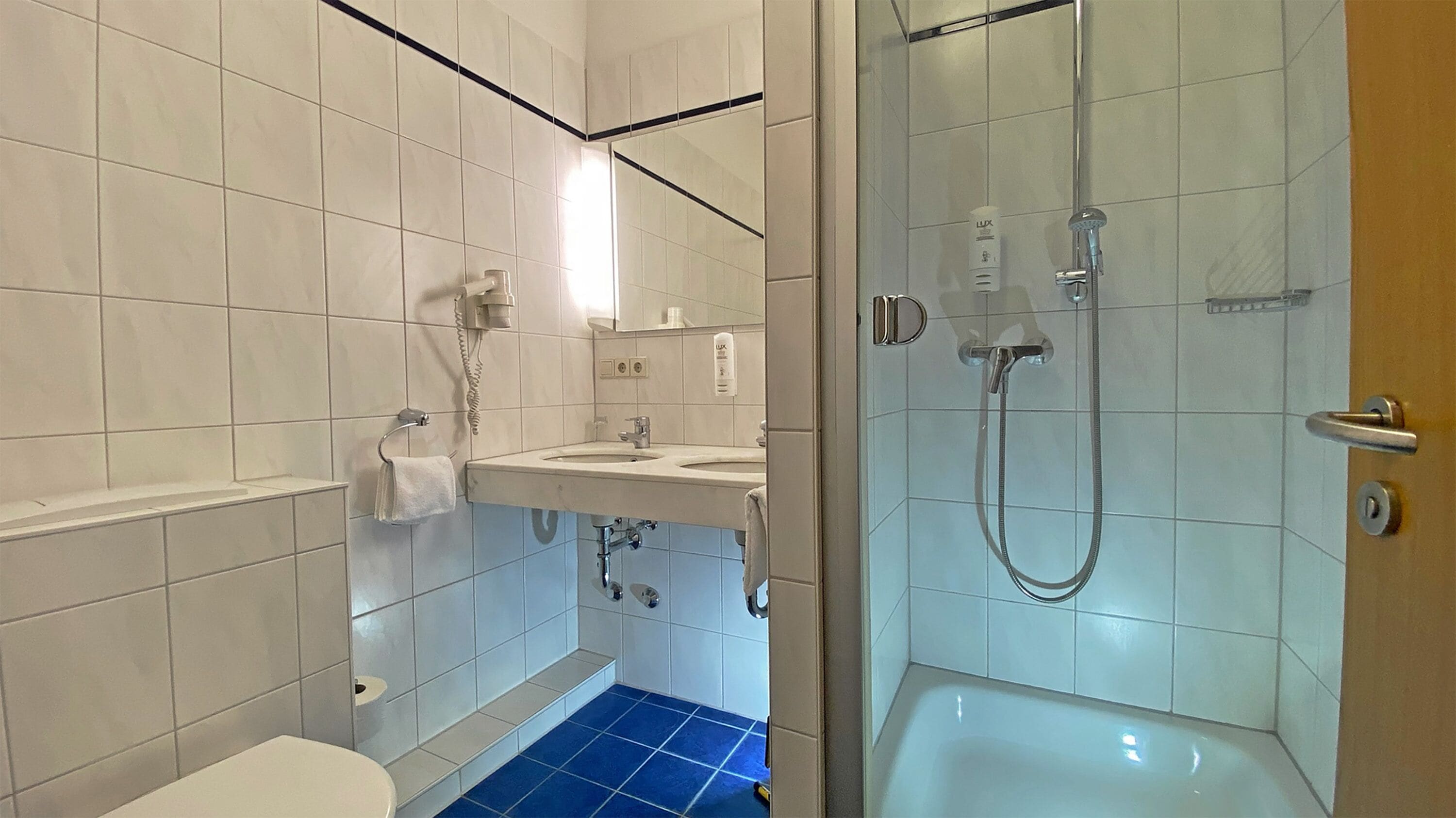 A bathroom with a toilet, sink, and shower.