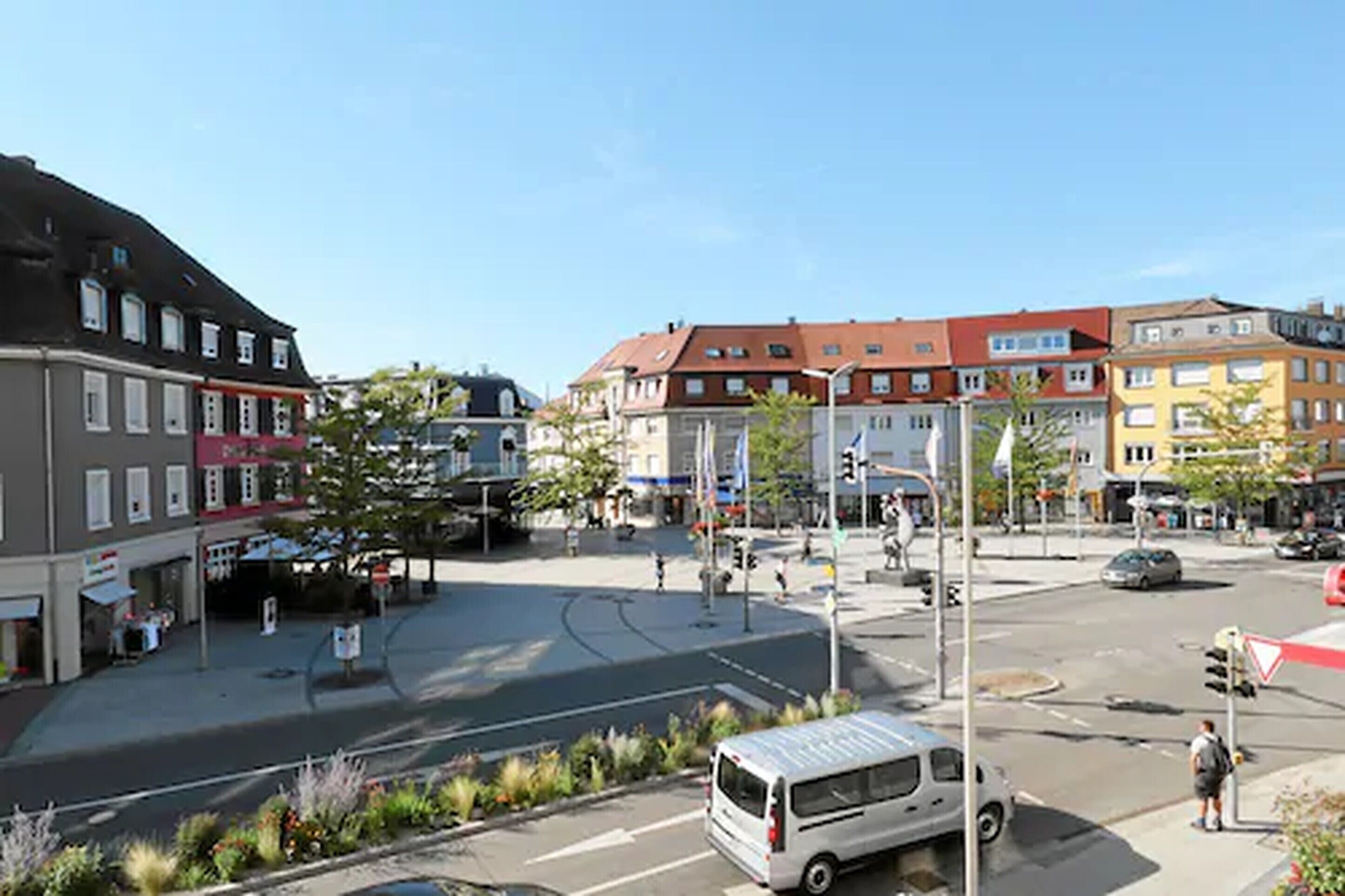 Une intersection dans une ville, avec des immeubles, un fourgon et des piétons.