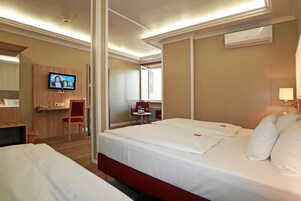 Habitación de hotel con dos camas, un escritorio, una silla, un televisor y un aire acondicionado.