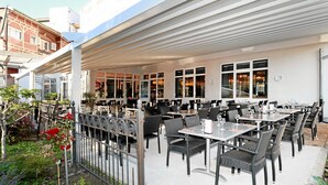 An outdoor patio area with tables and chairs, a covered seating area, and a view of the street. - Hotel & Restaurant Danner (Rheinfelden (Baden))