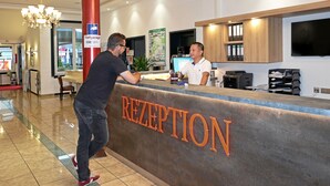 A reception area with a reception desk labeled "RECEPTION," a chandelier, a red pillar, and a map on the wall. - Hotel & Restaurant Danner (Rheinfelden (Baden))