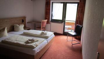 Ein Hotelzimmer mit zwei Betten, einem kleinen Tisch, einem Stuhl und Blick nach draußen.