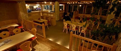 A restaurant with wooden furniture, a bar area, and a view of the street.