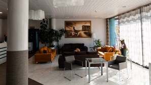 Un'ampia hall dall'arredamento moderno, con un divano grande, un tavolino da caffè e un'ampia finestra con tende.