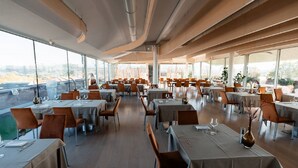 Un ristorante spazioso con numerosi tavoli e sedie, ampie finestre che offrono vista sulla città.
