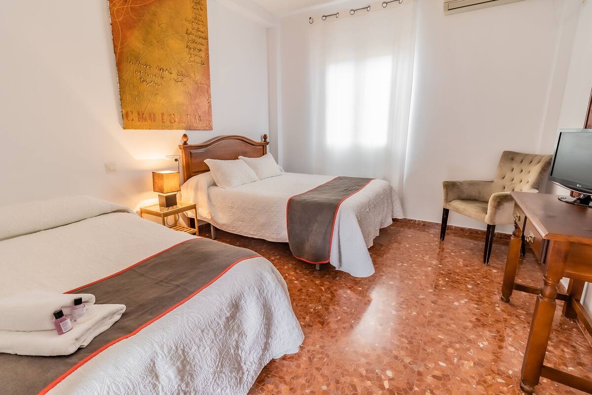 Ein Hotelzimmer mit zwei Betten, einem Schreibtisch, einem Stuhl und einem Fernseher.
