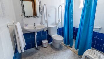 Baño con lavamanos, inodoro y cortina de ducha.