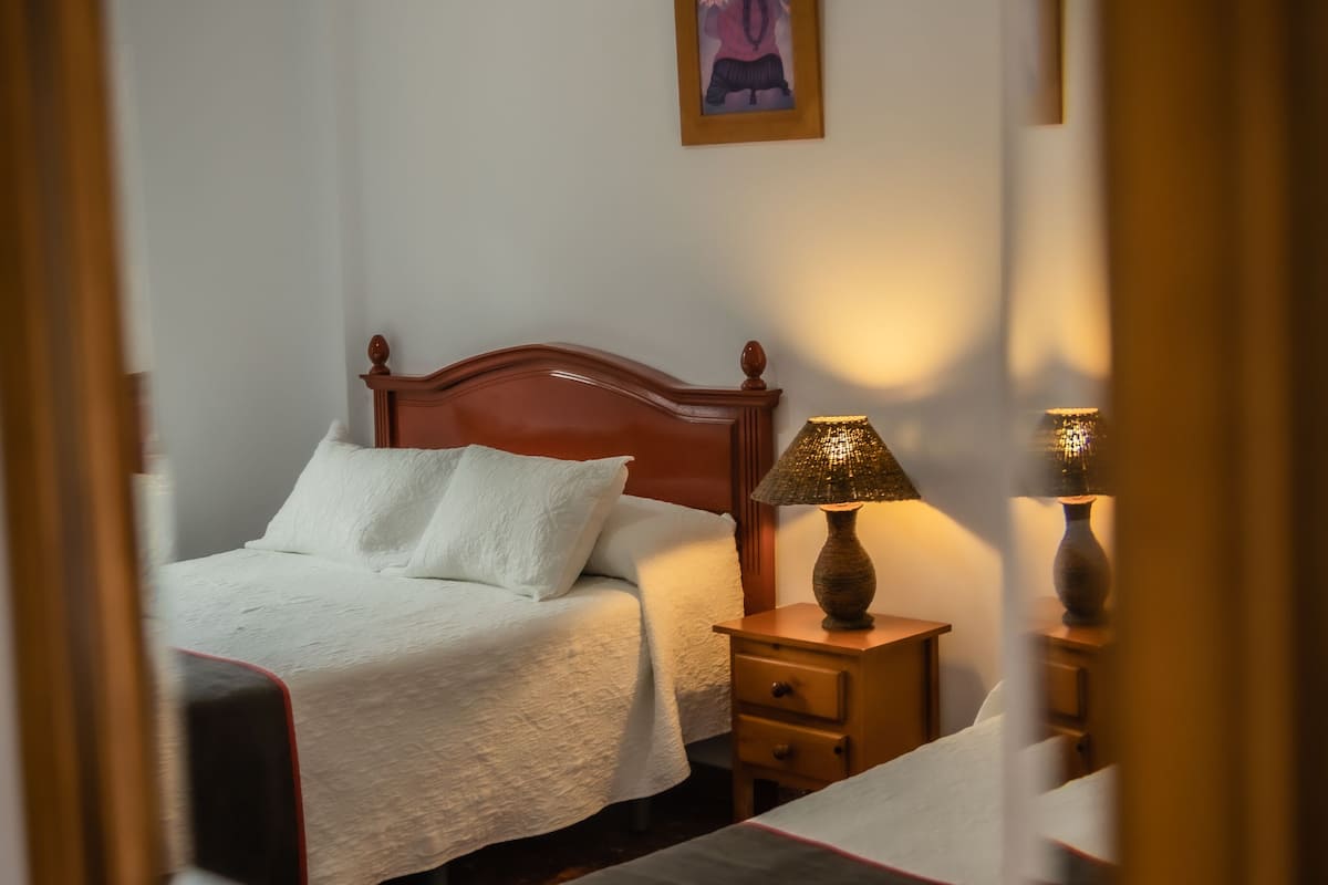 Ein Schlafzimmer mit einem hölzernen Bett, einem Nachttisch mit Lampe und einem gerahmten Bild an der Wand.