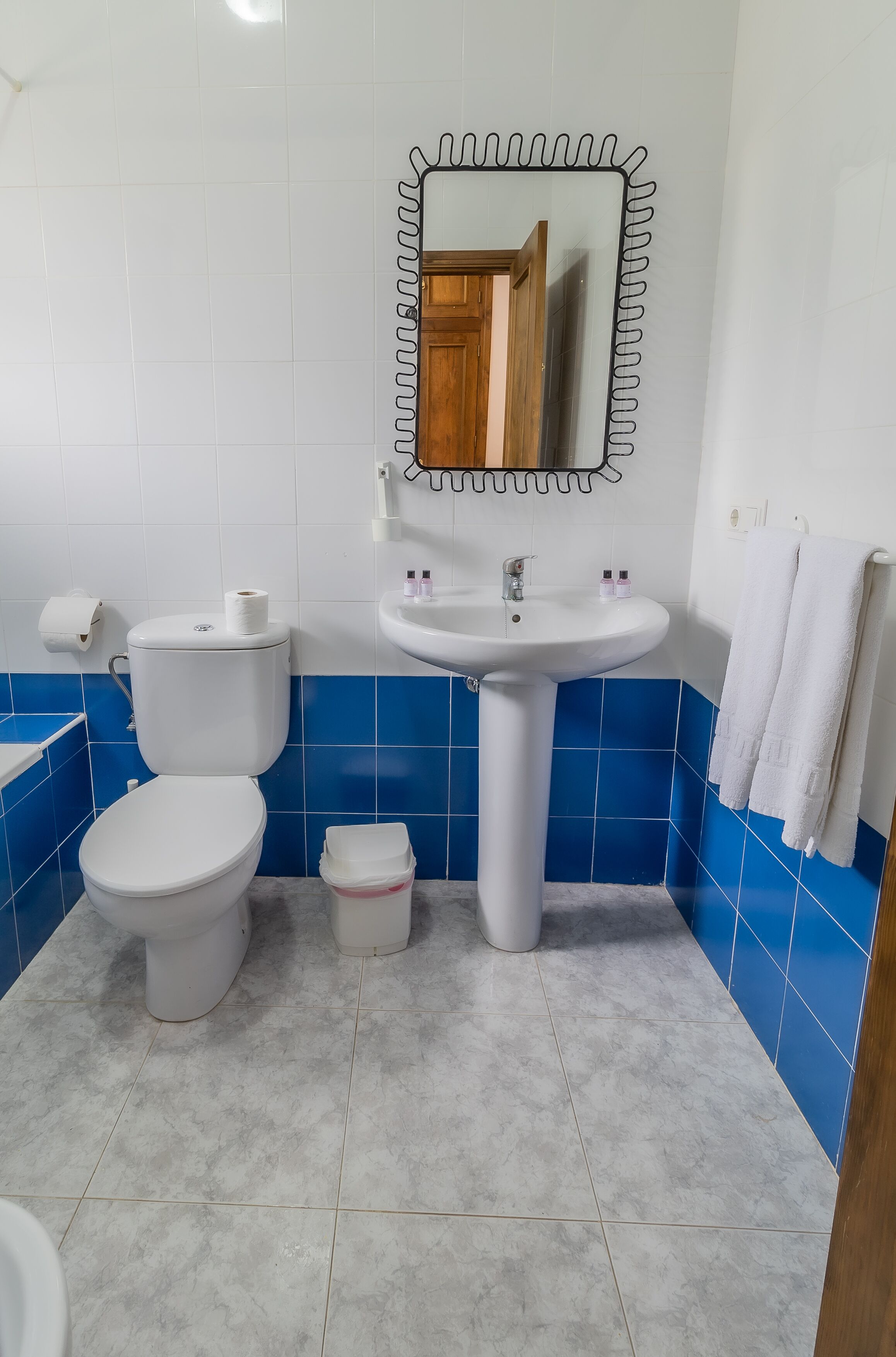 A bathroom with a toilet, sink, and mirror.