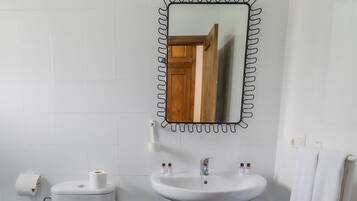 A bathroom with a toilet, sink, and mirror.