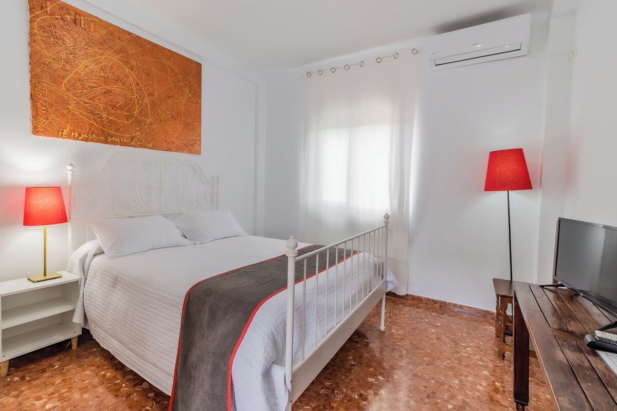 Une chambre à coucher avec un lit, une table de chevet, un téléviseur et une lampe rouge.