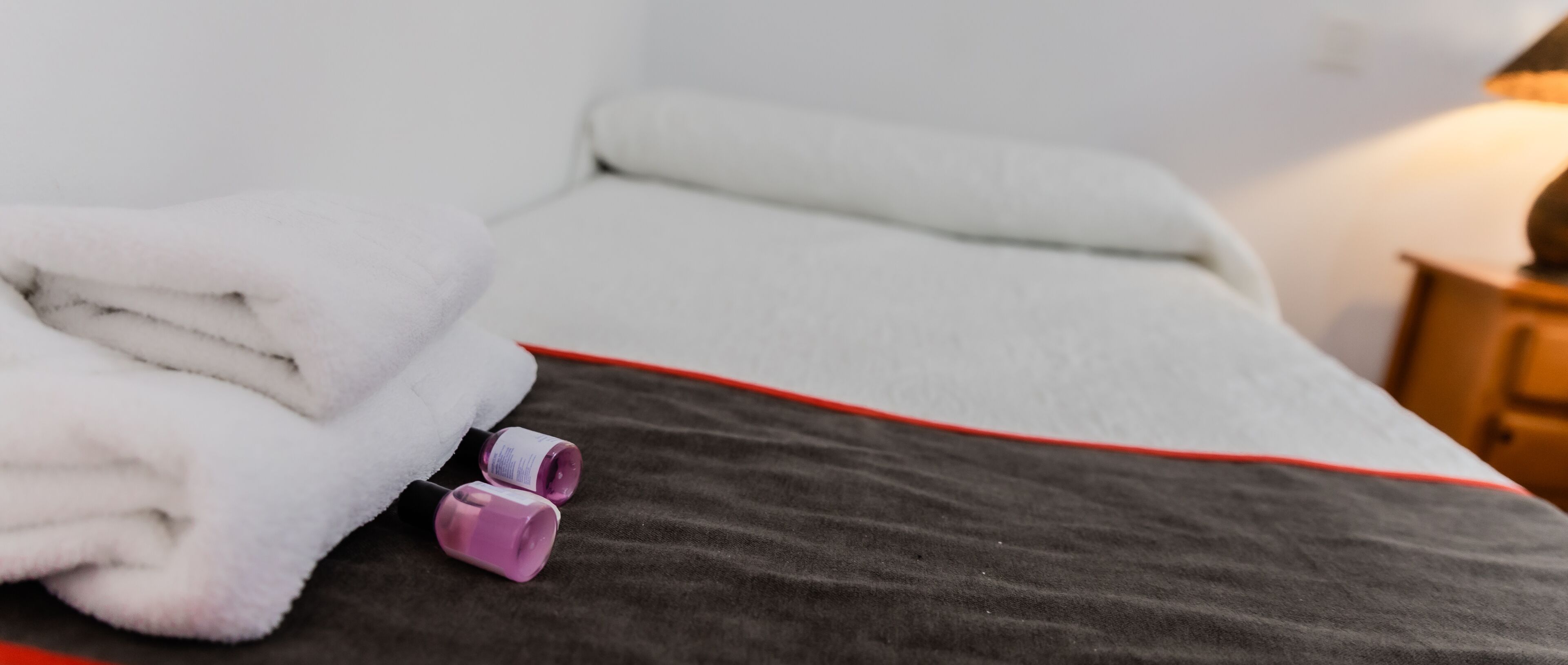Una cama bien hecha con una almohada blanca y una toalla blanca doblada.