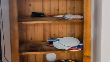 A wooden bookshelf with various items including a clock, a box labeled 'Master Paper Copy', and several tennis rackets.