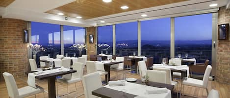 Un comedor moderno con ventanas amplias, techo de madera y paredes de ladrillo.