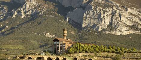 A building with a tower, a stone bridge, and a mountainous backdrop.