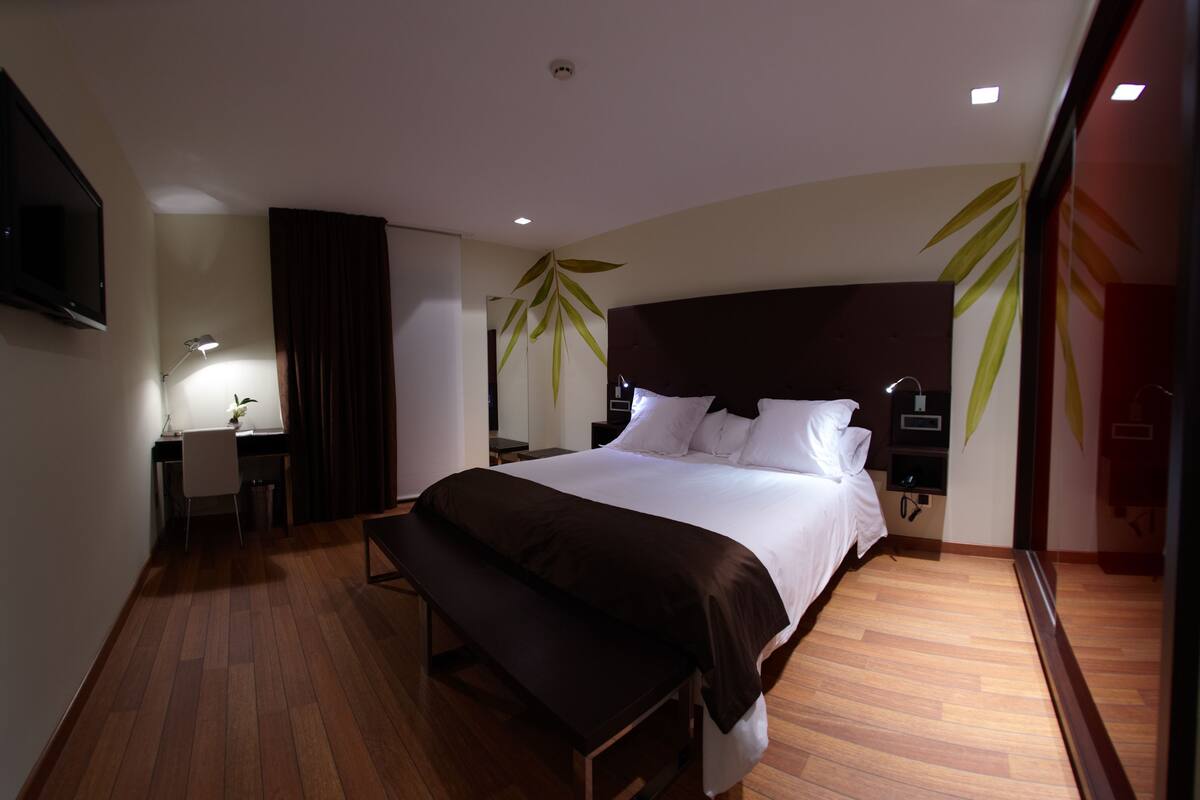 Ein modernes Hotelzimmer mit einem großen Bett, einem Schreibtisch und einem Fernseher.