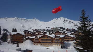 A snow-covered mountain resort with wooden chalets and a ski lift in the background.