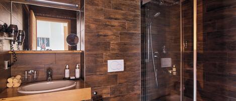 A modern bathroom with a wooden vanity, a glass shower enclosure, and a large mirror.