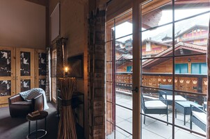 Una habitación acogedora con un ventanal grande, una silla de madera y una mesa.