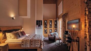 Ein gemütliches Schlafzimmer mit einem Holzbett, einem Sessel, einem kleinen Tisch und einer dekorativen Lampe.