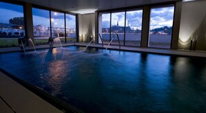 An indoor swimming pool with a view of a cityscape through large windows. - Villa Batalha (Batalha)