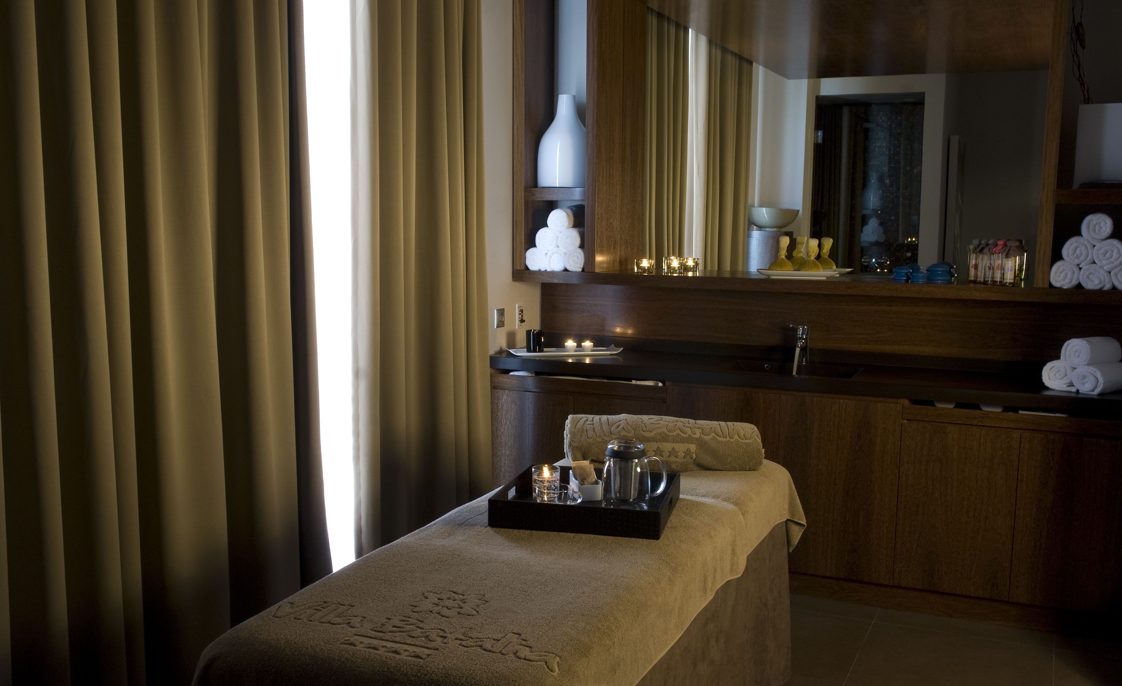 Une salle de spa équipée d’une table de massage, d’un plateau avec des articles de toilette, d’un miroir et de serviettes.