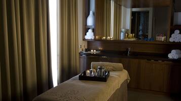 Une salle de spa équipée d’une table de massage, d’un plateau avec des articles de toilette, d’un miroir et de serviettes.