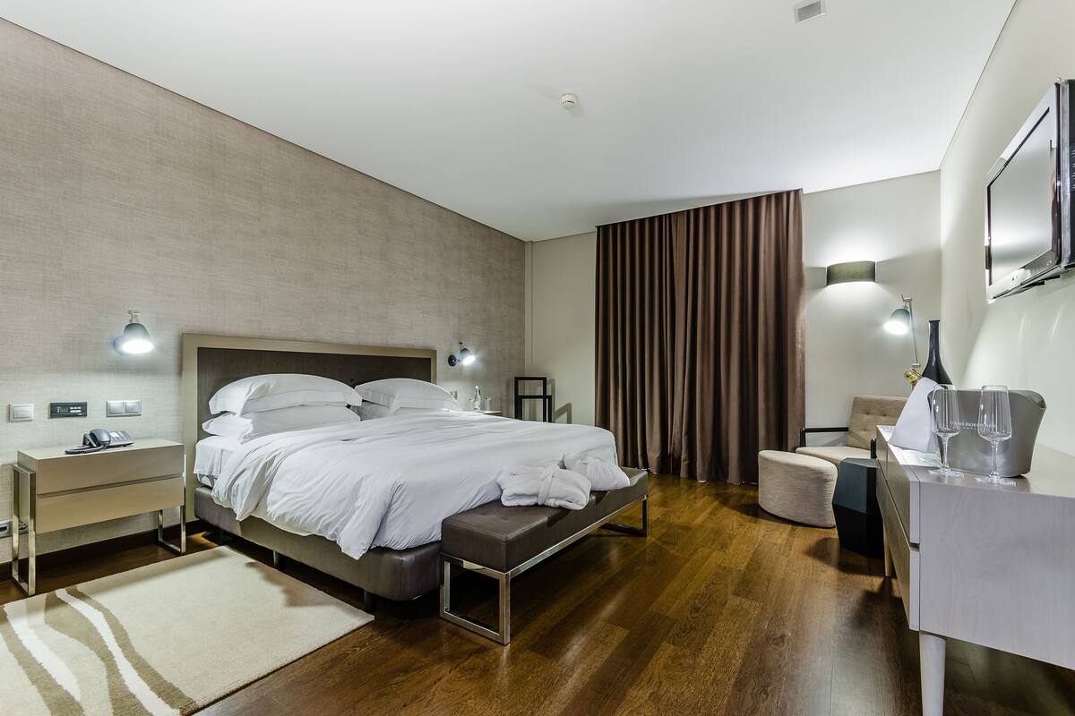 A modern hotel room with a large bed, bedside tables, a desk, and a chair.