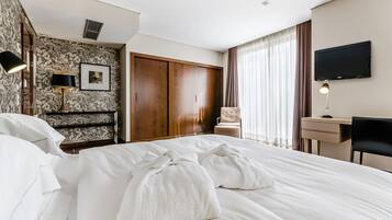 Una habitación de hotel con una cama grande, un escritorio, una silla, un televisor y un armario.