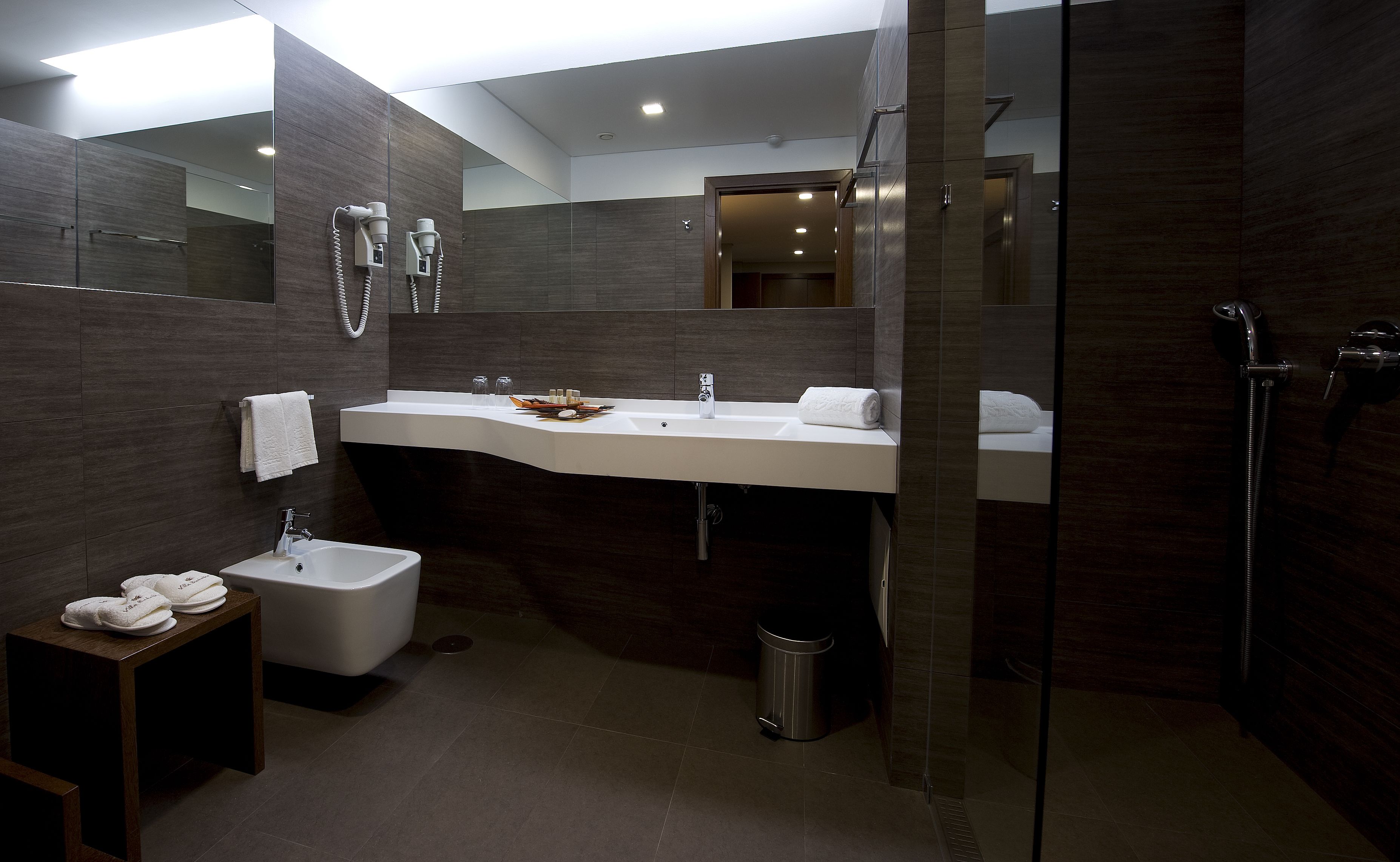 A modern bathroom with a large mirror, a sink, a toilet, and a shower area.