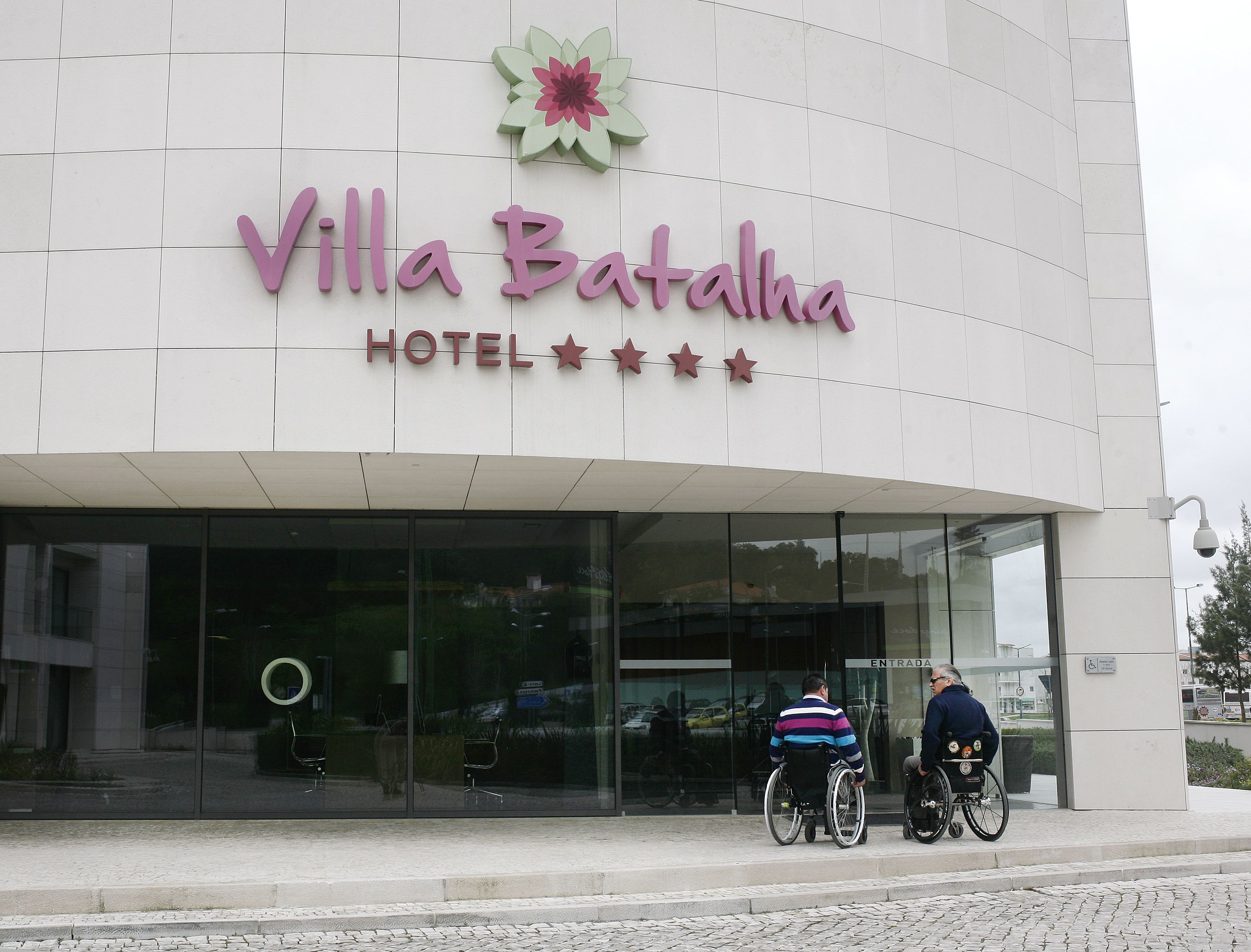 Exterior del hotel Villa Batista con fachada moderna, amplio acceso de vidrio y accesibilidad para sillas de ruedas.