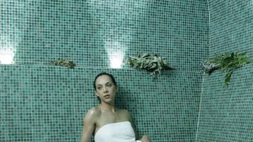 A room with a tiled wall and a single white slipper on the floor.
