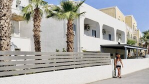 Un edificio blanco con ventanas arqueadas y una palmera al frente.