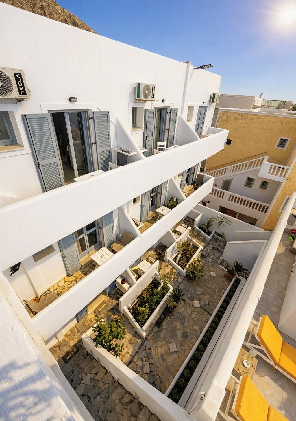 A multi-story building with balconies, outdoor seating, and planters.