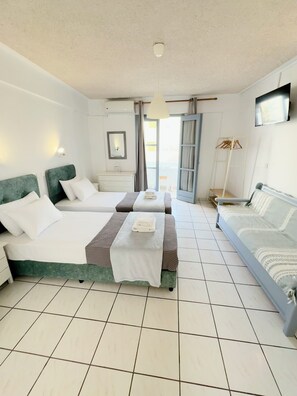 A hotel room with two beds, a TV, a wardrobe, and a balcony. - Zacharakis Studios (Santorini)