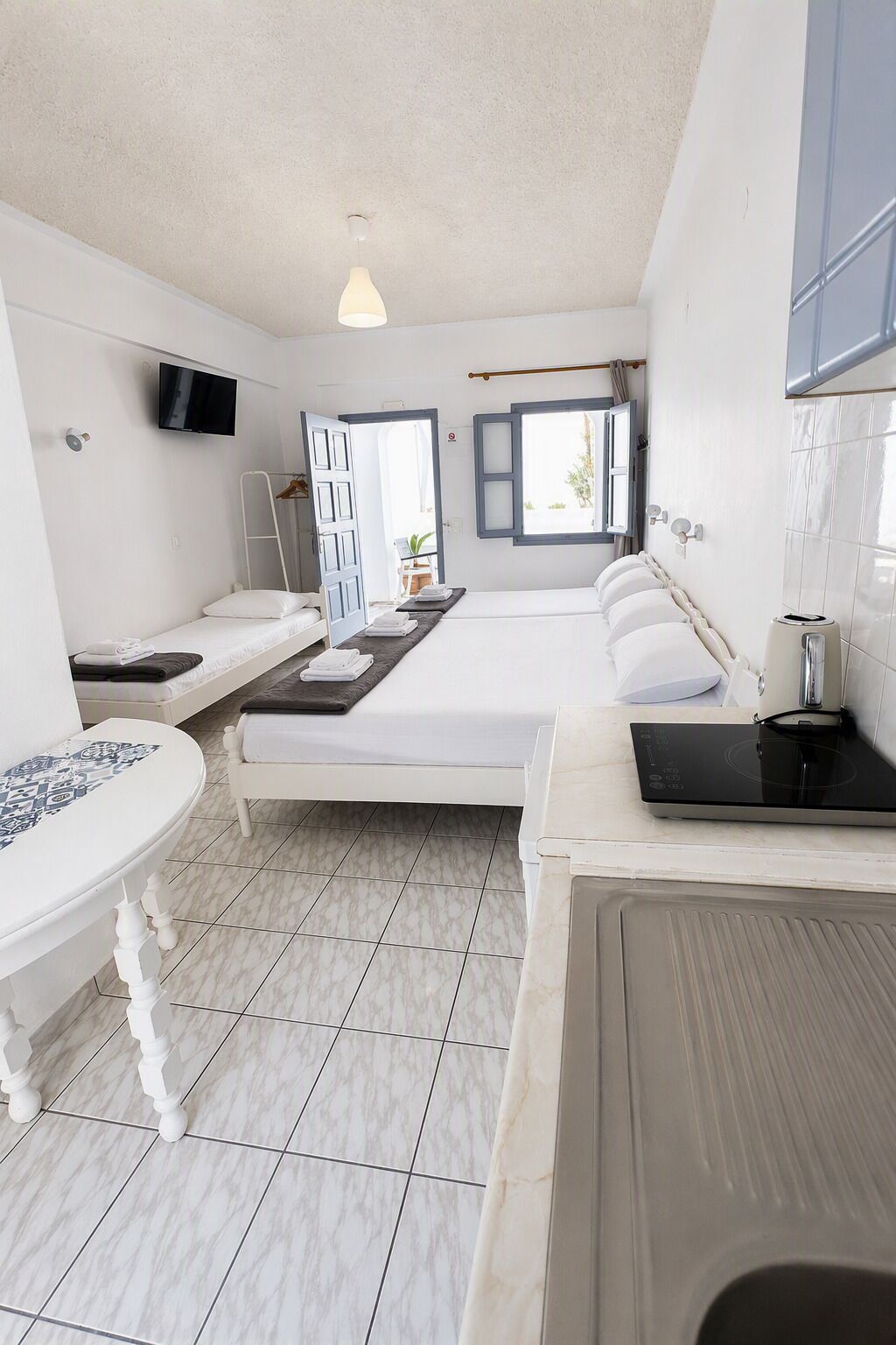 A hotel room with a bed, a desk, a chair, a TV, and a window.
